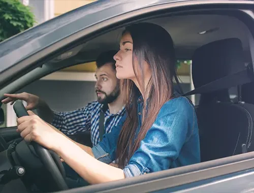 Calm driving instructor supporting a nervous learner in an automatic lesson